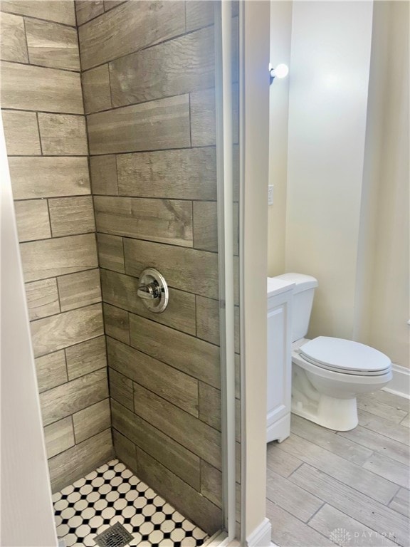 bathroom featuring tiled shower, wood-type flooring, and toilet