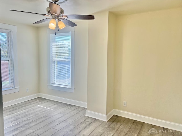 empty room featuring ceiling fan, light wood-type flooring, and a wealth of natural light