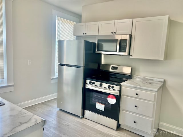 kitchen featuring white cabinetry, light hardwood / wood-style floors, a healthy amount of sunlight, and appliances with stainless steel finishes