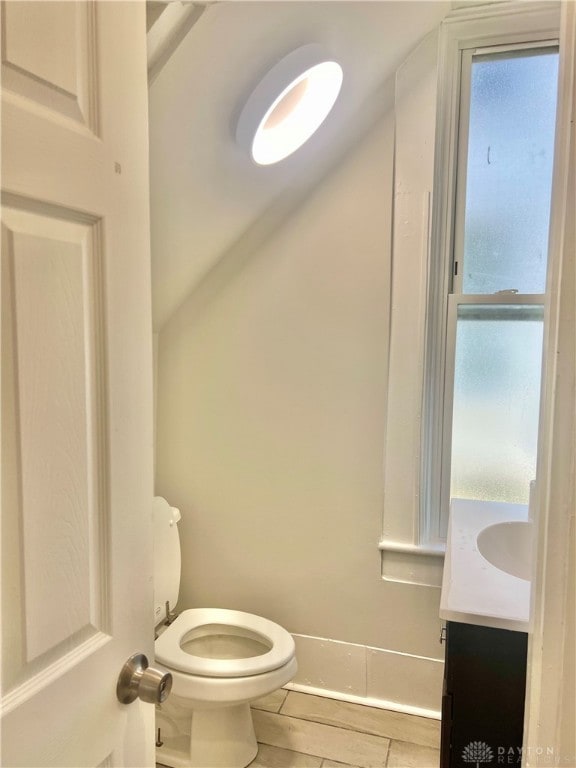 bathroom featuring vanity, lofted ceiling, and toilet