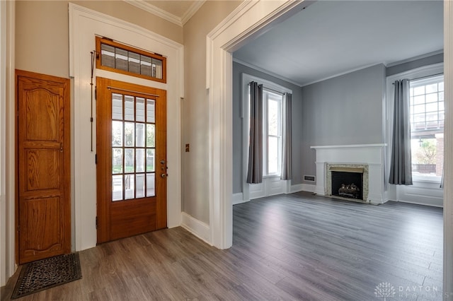 entrance foyer with a fireplace with flush hearth, crown molding, baseboards, and wood finished floors