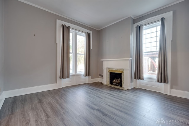 unfurnished living room with plenty of natural light, dark wood-style flooring, crown molding, and a premium fireplace