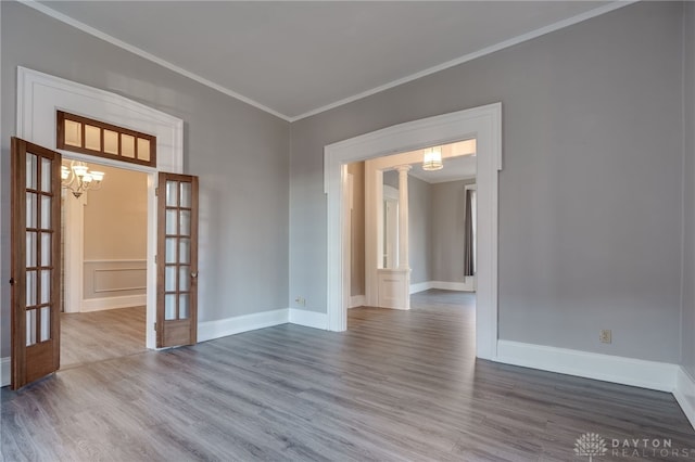 empty room with baseboards, ornamental molding, wood finished floors, and french doors