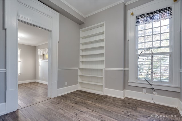 interior space with dark wood-style floors, baseboards, built in shelves, and ornamental molding