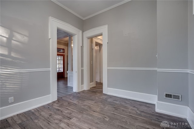 unfurnished room with baseboards, visible vents, wood finished floors, and ornamental molding