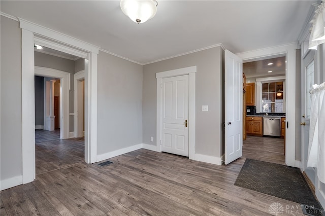 empty room with dark wood-style floors, baseboards, visible vents, and ornamental molding