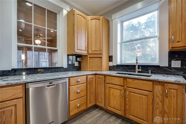 kitchen featuring light stone counters, backsplash, crown molding, stainless steel dishwasher, and a sink