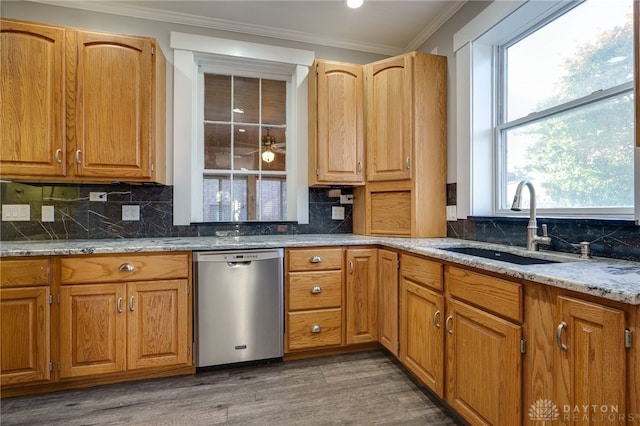 kitchen with wood finished floors, a sink, stainless steel dishwasher, tasteful backsplash, and crown molding