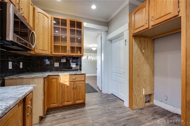 kitchen featuring ornamental molding, stainless steel microwave, wood finished floors, and tasteful backsplash