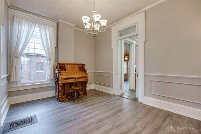 dining room featuring visible vents, ornamental molding, an inviting chandelier, a textured ceiling, and light wood-type flooring