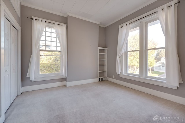 carpeted spare room featuring ornamental molding, visible vents, and baseboards