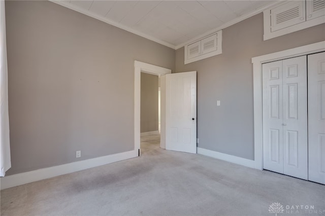 unfurnished bedroom with baseboards, a closet, ornamental molding, and carpet flooring