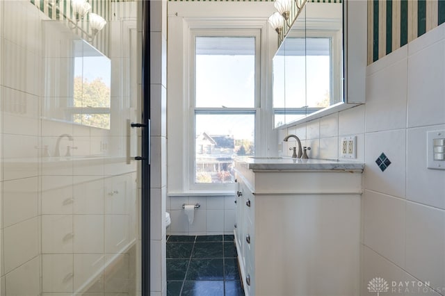 full bathroom with a stall shower, toilet, tile patterned flooring, vanity, and tile walls