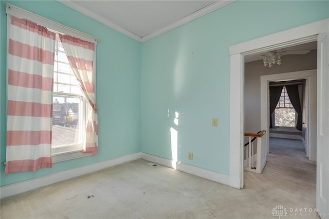 carpeted empty room featuring baseboards, ornamental molding, visible vents, and a healthy amount of sunlight