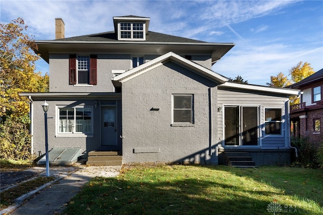 traditional style home featuring entry steps, brick siding, and a front yard