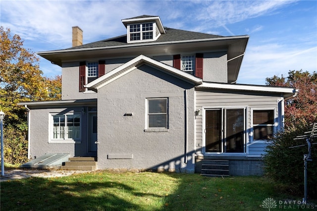 rear view of property featuring entry steps, brick siding, and a lawn