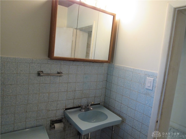 bathroom featuring sink and tile walls