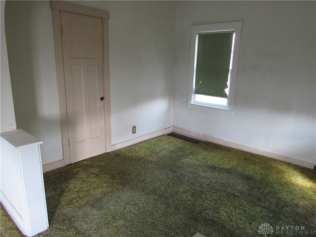 unfurnished room featuring dark colored carpet