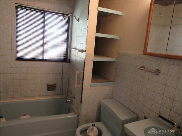 bathroom featuring toilet, tiled shower / bath combo, and tile walls