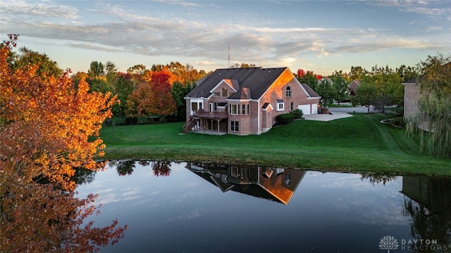 exterior space featuring a patio, a lawn, and a water view