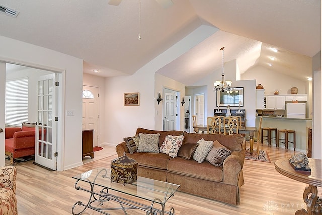 living room with vaulted ceiling, light hardwood / wood-style flooring, and ceiling fan with notable chandelier