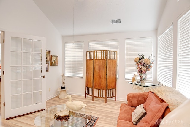 living area featuring high vaulted ceiling, light wood-type flooring, and plenty of natural light