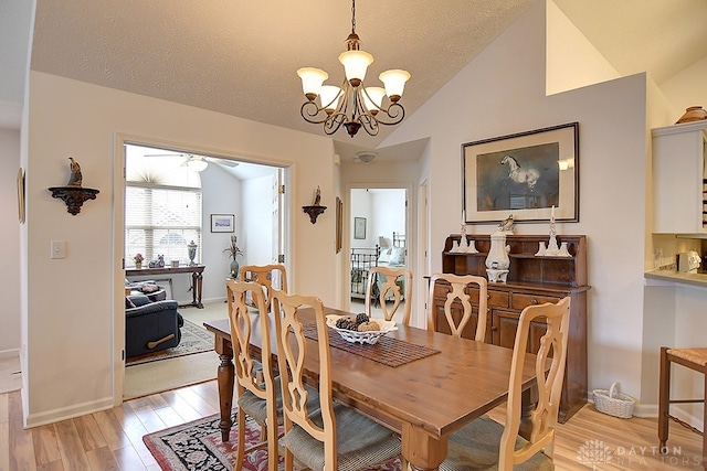 dining room featuring light hardwood / wood-style floors, a textured ceiling, lofted ceiling, and ceiling fan with notable chandelier