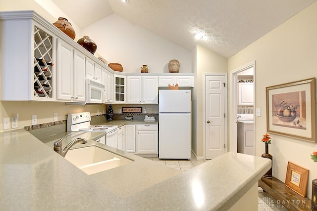 kitchen with washer / dryer, lofted ceiling, white cabinets, sink, and white appliances