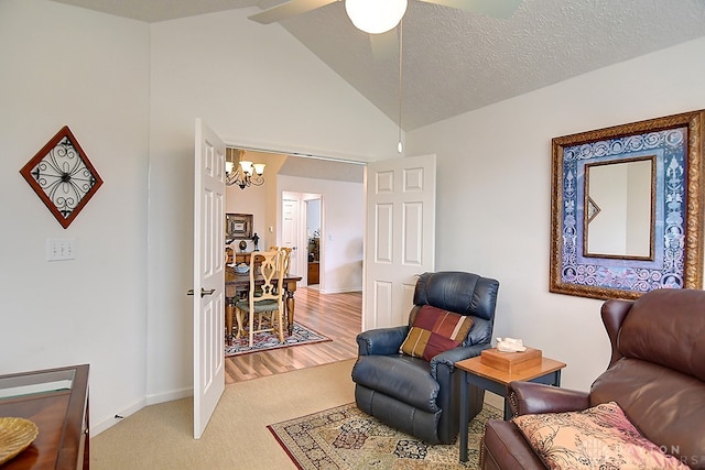 sitting room with high vaulted ceiling, a textured ceiling, ceiling fan with notable chandelier, and light hardwood / wood-style floors