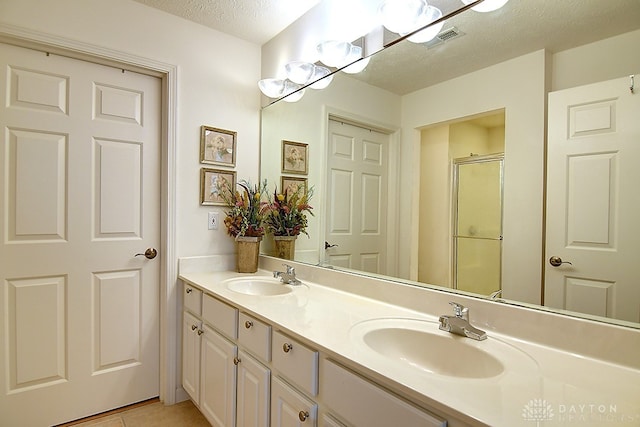 bathroom featuring a shower with door, a textured ceiling, tile patterned flooring, and vanity