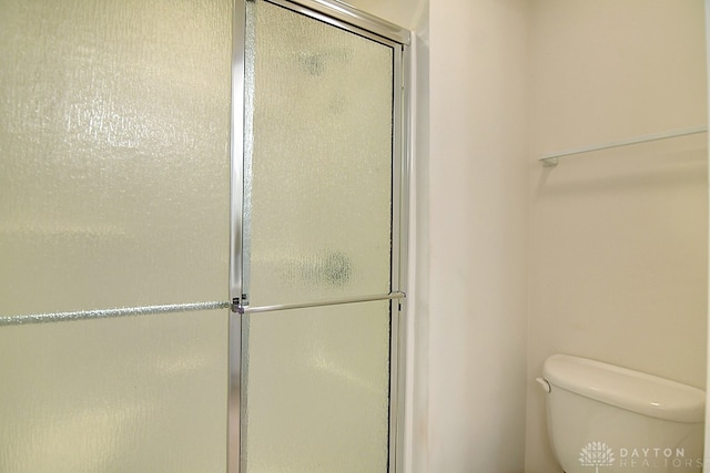 bathroom with a shower with door and toilet