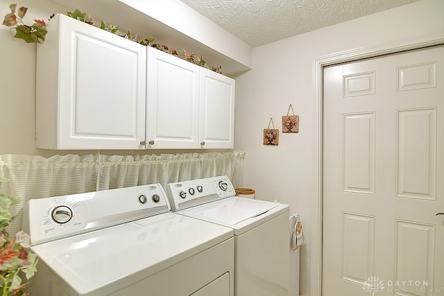 washroom featuring cabinets, a textured ceiling, and washing machine and clothes dryer