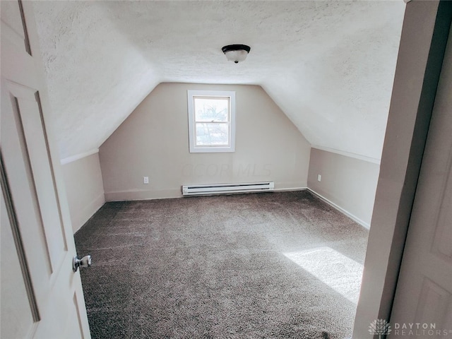 additional living space with vaulted ceiling, a textured ceiling, a baseboard heating unit, and carpet floors