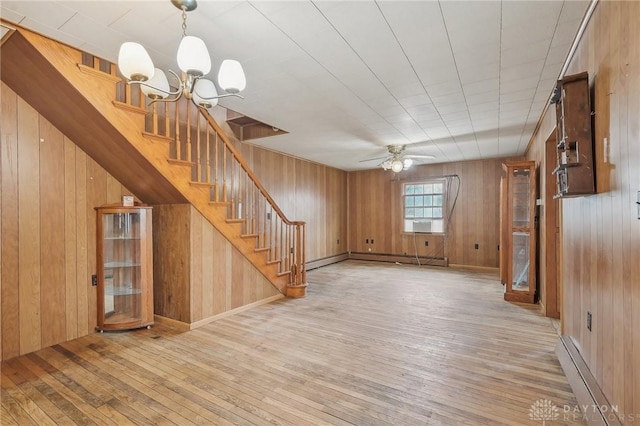 unfurnished living room with a baseboard radiator, hardwood / wood-style floors, and wood walls