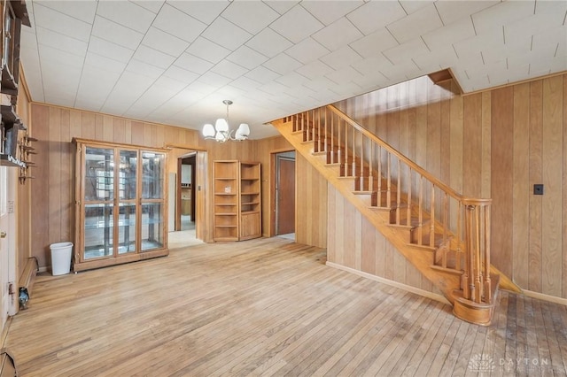 interior space featuring an inviting chandelier, wooden walls, and light wood-type flooring