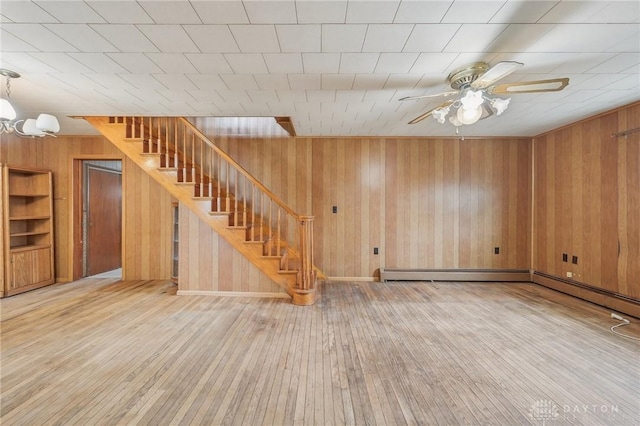 interior space featuring hardwood / wood-style flooring, ceiling fan with notable chandelier, and wood walls