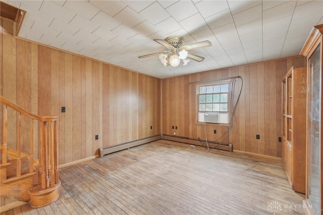 spare room featuring ceiling fan, wooden walls, light hardwood / wood-style floors, and baseboard heating