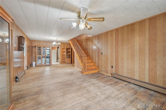 interior space featuring wood-type flooring, ceiling fan with notable chandelier, baseboard heating, and wood walls