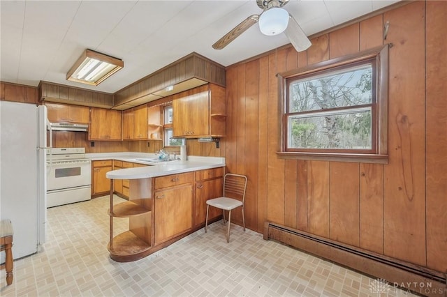 kitchen featuring sink, white appliances, wooden walls, a baseboard radiator, and kitchen peninsula