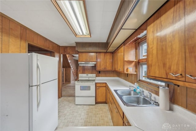 kitchen with sink, white appliances, and wooden walls