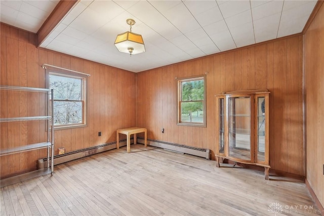 empty room featuring a baseboard radiator, light hardwood / wood-style floors, and a healthy amount of sunlight