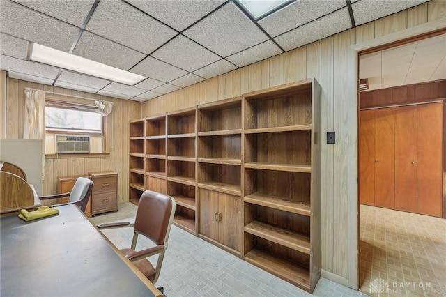 office featuring cooling unit, a drop ceiling, and wood walls