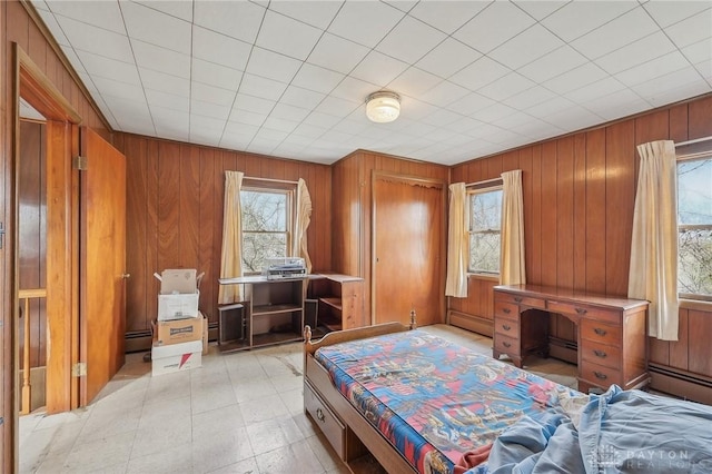 bedroom featuring a baseboard radiator and wood walls