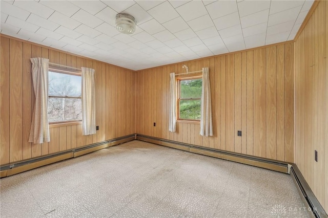 spare room with a baseboard heating unit and wood walls