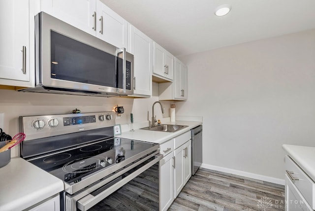 kitchen with sink, appliances with stainless steel finishes, light wood-type flooring, and white cabinets