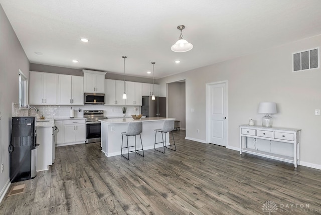 kitchen featuring white cabinetry, stainless steel appliances, a kitchen island, and hanging light fixtures