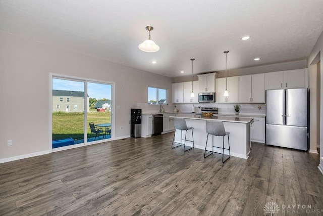 kitchen featuring a center island, appliances with stainless steel finishes, decorative light fixtures, and white cabinets