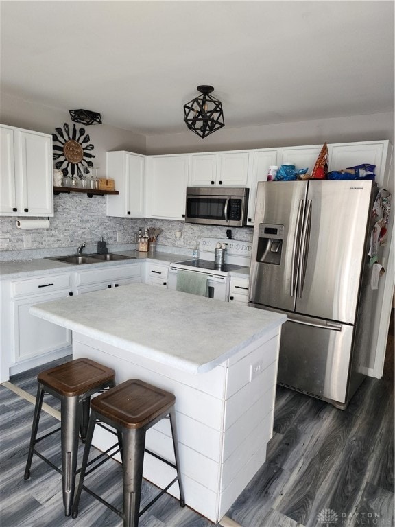 kitchen featuring sink, a kitchen breakfast bar, white cabinetry, stainless steel appliances, and dark hardwood / wood-style floors