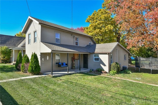 rear view of property with a yard, cooling unit, a trampoline, and a patio area