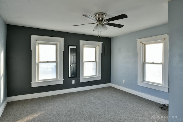 spare room with ceiling fan, carpet flooring, and a wealth of natural light